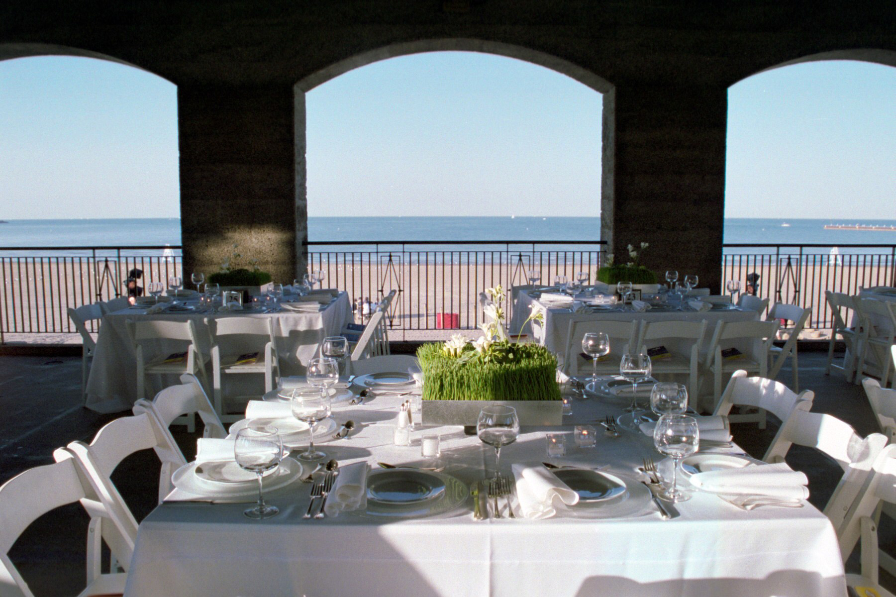 Elegant beachside reception with white tablecloths, place settings, and ocean view.